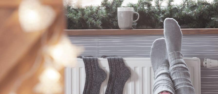 Woman warming up with feet on a heater